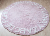 Tapis rond rose avec des lettre blanche