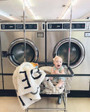 Dans une laverie le bébé rigole devant les machnine a laver avec les tapis rond lettre