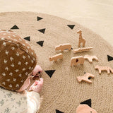 Mise en situation d'un enfant qui joue avec des petit joué en bois sur le tapis rond jute