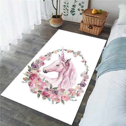Une licorne avec un bouquet de rose autour de la tête ces le motif qu'a ce tapis de chambre fille