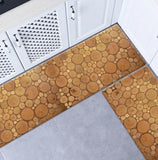 Deux tapis de cuisine aux motifs tranches de bois de tailles différents, marron beige, posés au pied d'un cuicine aménagé en angle, mmeubles blanc, sol gris clair.