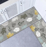 Tapis de cuisine feuilles blanches, grises, dorés sur fond gris au pied d'une cuisine aménagé aux meubles blanc