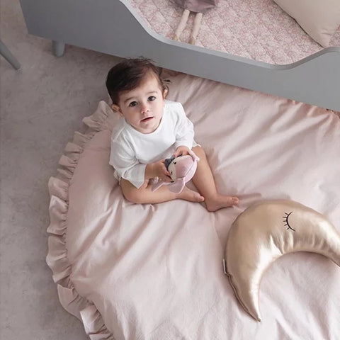 Jeune fille bébé assis sur ce tapis rond moelleux en coton