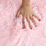 Jeune main sur les fibres de ce tapis confortable rose pale