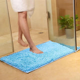 Femme qui pose le pied sur le tapis de salle de bain très absorbant couleur bleu ciel