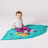 Photos où on voit un bébé assis sur ce tapis feuille couleur turquoise