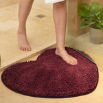 Photos où l'on voit les jambes d'une dame marcher sur ce tapis de salle de bain cœur couleur violet